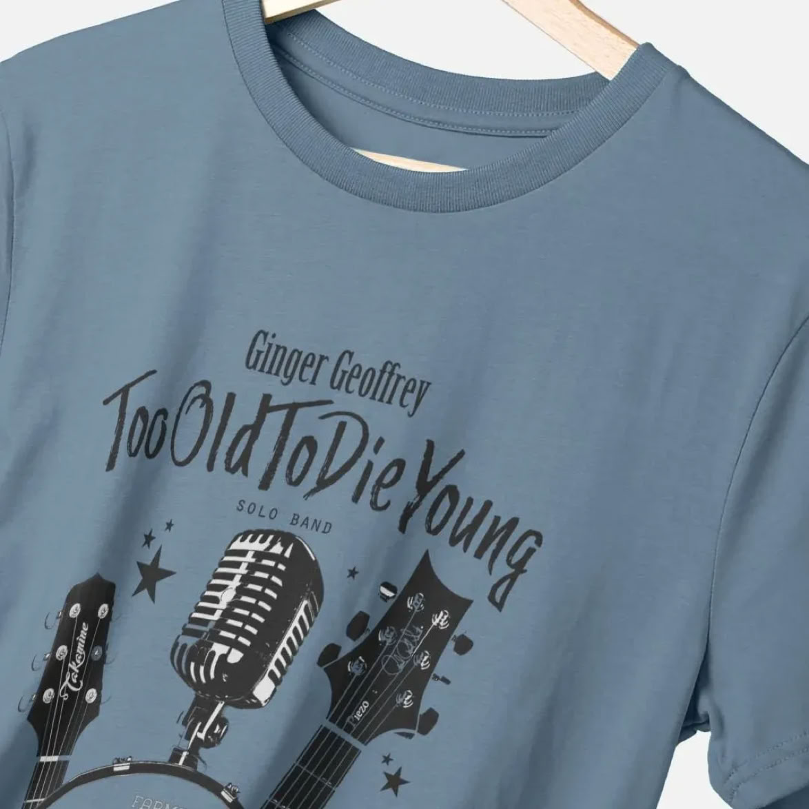 Light Blue Ginger Geoffrey Too Old To Die Young T-Shirt Showing  Guitars, Mircorphone and Bass Drum
